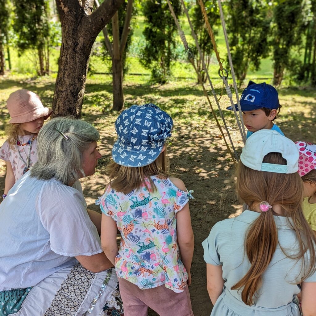 Vaikai ir auklėtoja miške, sutūpę ratu